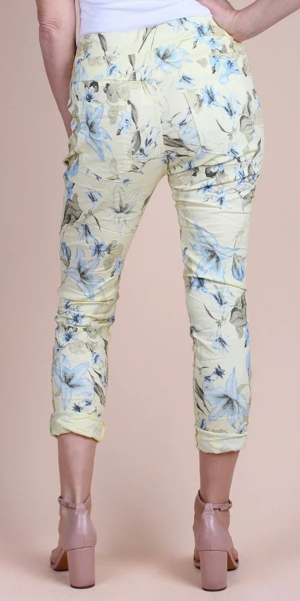 Back view of cropped yellow floral pants with blue and grey flower print, rolled cuffs