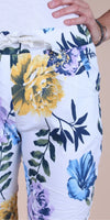 White floral print pants with yellow, blue, and purple flowers, linen texture, woman’s hand on waist