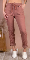 Women's crinkled rose-colored linen pants with tie waist, rolled cuffs, and side pockets