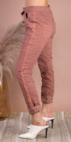 Side view of woman wearing dusty pink tapered pants with side stripe and rolled cuffs