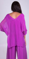 Woman wearing a sheer magenta V-neck top and matching wide-leg pants, back view
