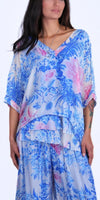 Woman wearing a loose blue and pink floral print silk blouse and matching pants