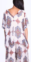 Woman wearing sheer silk top and pants with ornate multicolor print, back view