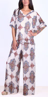 Woman wearing wide-leg pants and a loose top with colorful baroque floral print