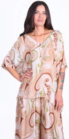 Woman modeling loose beige and green abstract print silk blouse and pants set