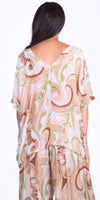 Woman wearing loose beige and green swirl print top and pants set, viewed from back