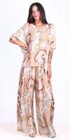 Woman wearing loose, flowy pants and top set with beige and green abstract pattern