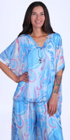 Woman wearing flowy blue and pink abstract print silk blouse and matching wide-leg pants