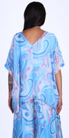 Woman wearing flowy blue and pink abstract print top and pants set, back view