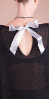 Close-up of sheer black top with silver ribbon bow at back keyhole detail