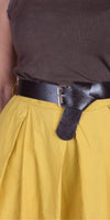 Black leather belt on yellow skirt with brown ribbed top, close-up fashion detail