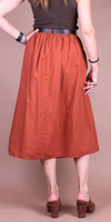 Back view of woman wearing rust midi skirt with gathered waist and block heel sandals