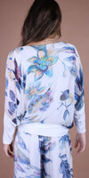 Back view of woman wearing white floral blouse and matching wide-leg pants