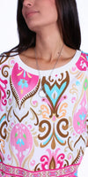 Woman wearing a colorful patterned blouse with pink, turquoise, and gold motifs