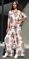 Woman wearing wide-leg patterned pants and matching flowy blouse in geometric floral print