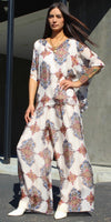 Woman wearing a flowy silk printed wide-leg pants and top set with floral patterns