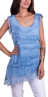 Woman wearing sleeveless blue layered silk tunic top with scoop neck, paired with white pants