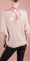 Back view of woman wearing beige knit sweater with open back and satin bow detail
