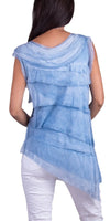 Woman in a sleeveless blue layered silk tunic top and white pants, back view