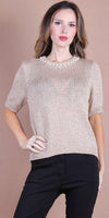 Woman wearing a beige knit short-sleeve sweater with pearl-embellished neckline