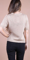 Back view of woman in beige knit short sleeve top and black pants