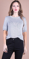 Woman wearing a light knit short sleeve top with pearl neckline and black pants