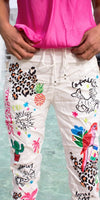 Woman wearing white pants with colorful tropical and animal print designs, pink top