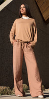 Woman wearing tan wide leg linen pants and loose long sleeve top, stylish neutral outfit