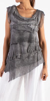 Sleeveless gray layered silk top with raw edges, paired with white wide-leg pants