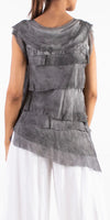 Back view of woman wearing a sleeveless layered grey silk top and white linen pants