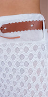 Close-up of white crochet knit skirt with brown scalloped leather belt and star cutout detail.