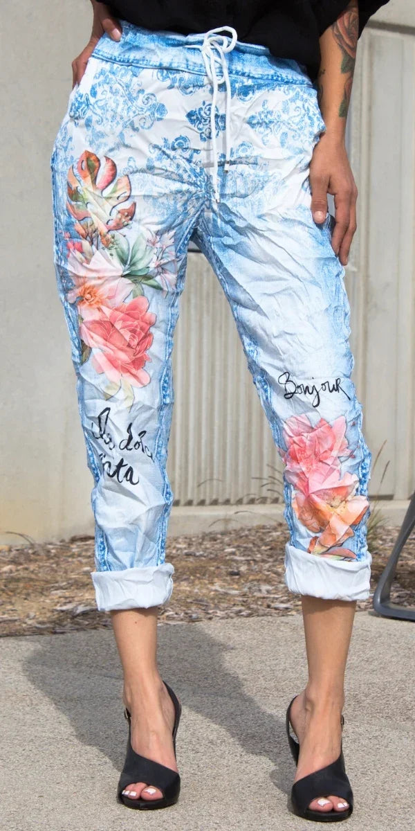 Women's light blue drawstring pants with floral prints and cursive script, rolled cuffs