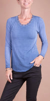Woman wearing a blue long sleeve top with lace trim and black pants