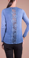 Blue long sleeve top with floral lace panel down the back, worn by woman with ponytail