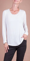 Woman wearing a white long sleeve top with lace neckline and black pants