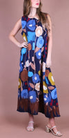 Woman wearing a sleeveless maxi dress with bold blue, yellow, and brown abstract floral print