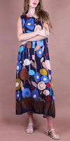 Woman wearing a sleeveless floral maxi dress with bold blue, brown, and yellow print