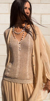 Woman wearing beige knit tank top, sheer lightweight cardigan, and pearl necklace, outdoors