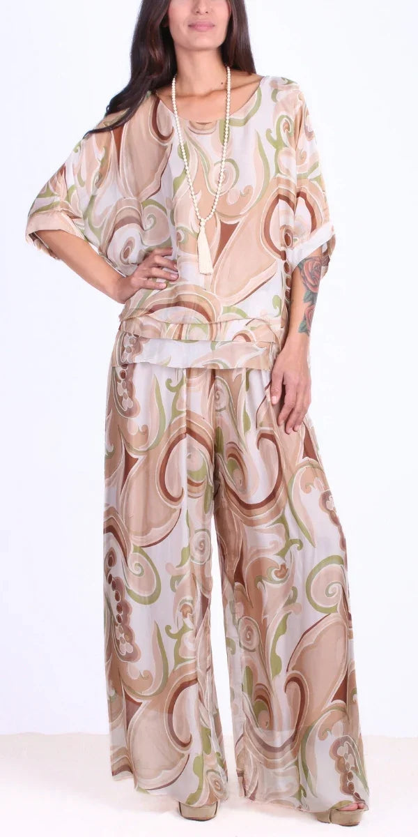Woman wearing flowy wide-leg pants and a loose top in beige and green swirled print