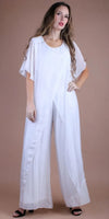 Woman in a white wide-leg silk jumpsuit with layered short sleeves, standing on neutral background