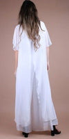 Back view of a woman wearing a flowing white silk jumpsuit with wide legs