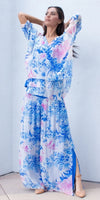 Woman wearing flowy blue and pink floral silk top and maxi skirt with side slit