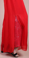 Red maxi skirt with front slit, sequin inner layer, and black open-toe sandal