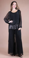 Woman wearing sheer black wide-leg pants and a sequin-embellished black blouse