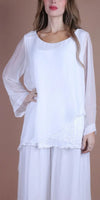 Woman wearing a white sheer silk blouse with layered long sleeves and sequin detail