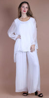 Woman wearing a white silk blouse with sheer sleeves and wide-leg pants, posing indoors