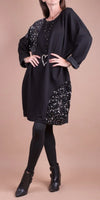 Woman wearing a black sequin-accented dress with black leggings and ankle boots
