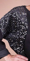 Black women's top with sequin-embellished batwing sleeve, close-up view