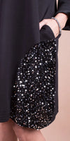Black dress with sequin-embellished pocket and beaded bracelet on model