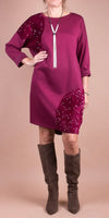 Woman wearing a magenta sequin-accented shift dress with knee-high suede boots